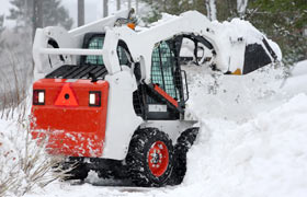 A skid steer plowing snow